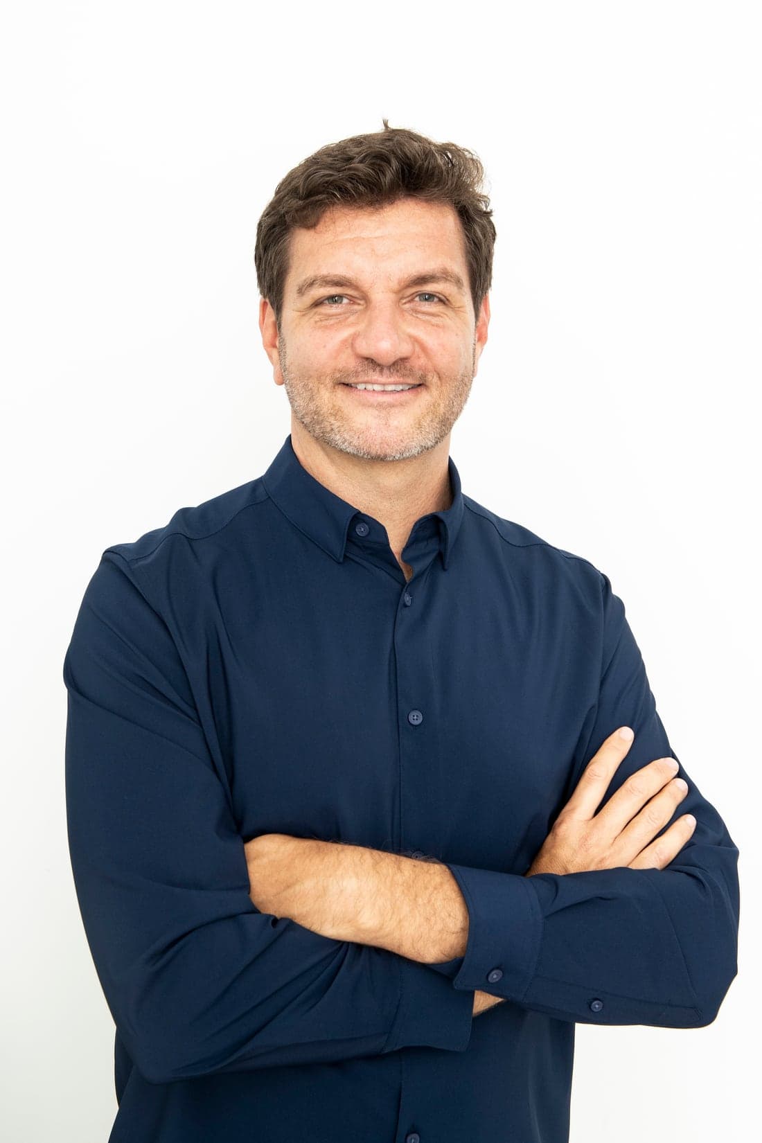 Retrato de Davis Genuino, de braços cruzados e camisa azul-marinho.
